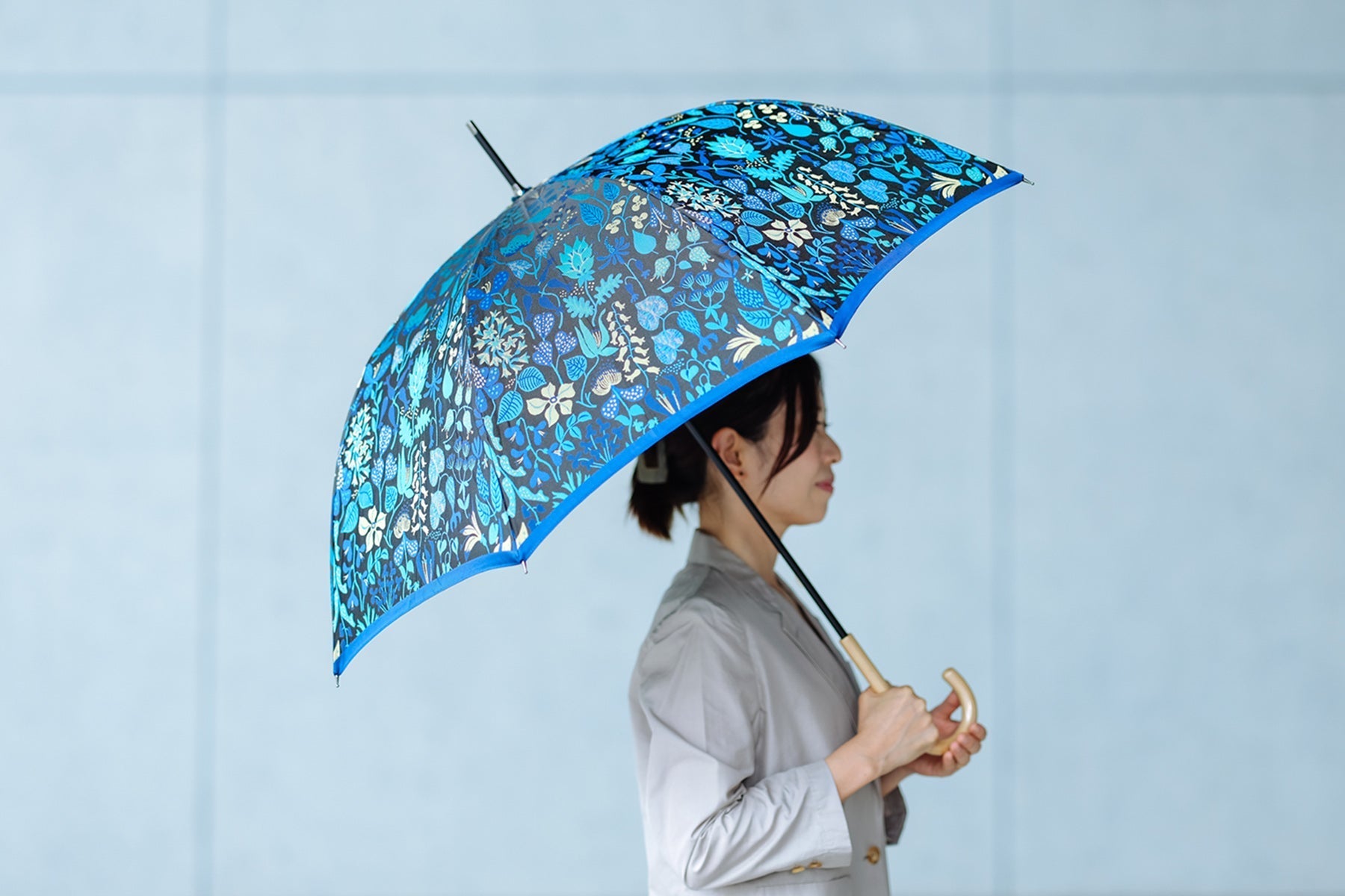 ブルーのハーバリウム柄の晴雨兼用傘を差す女性