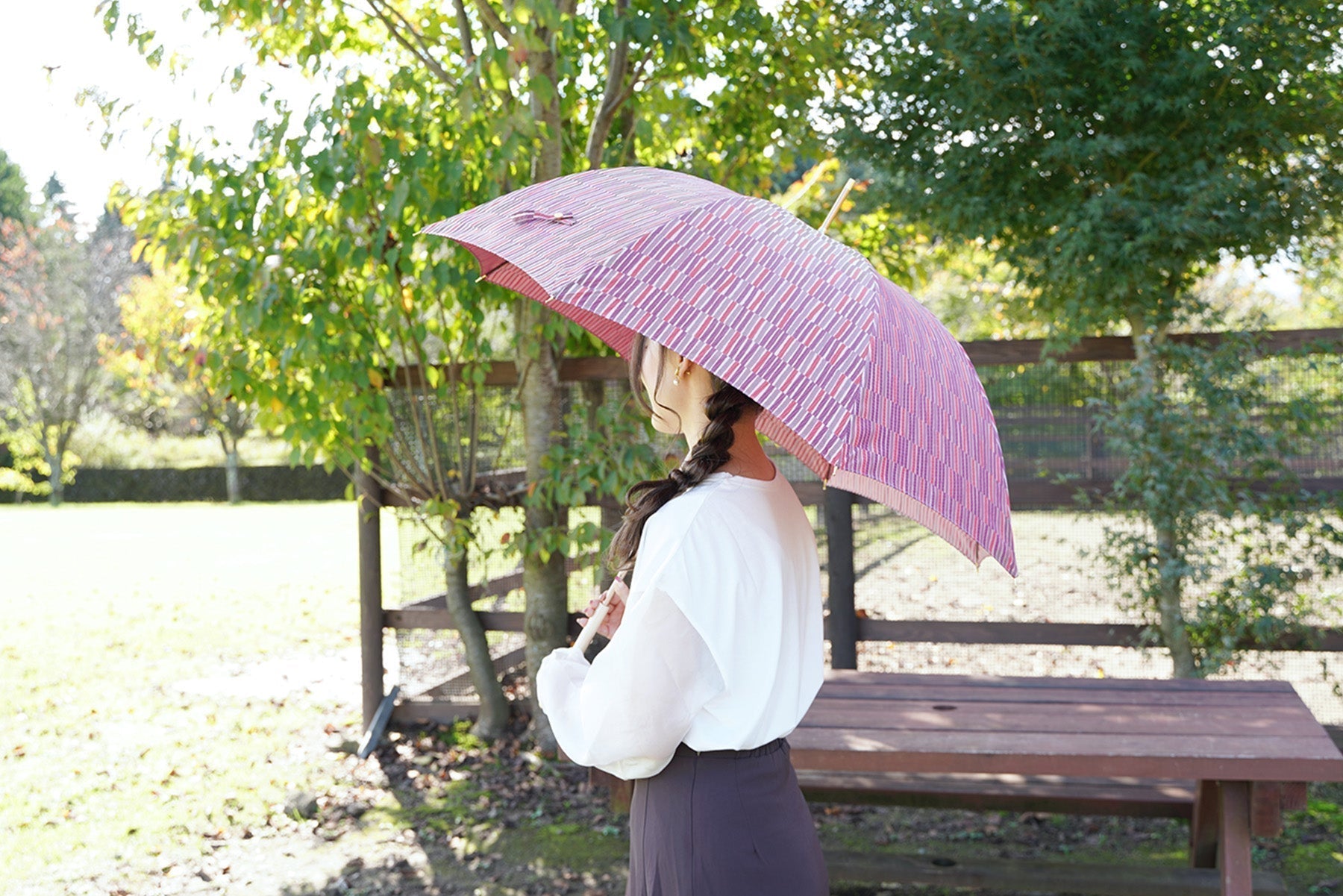 赤色の晴雨兼用傘をさす女性