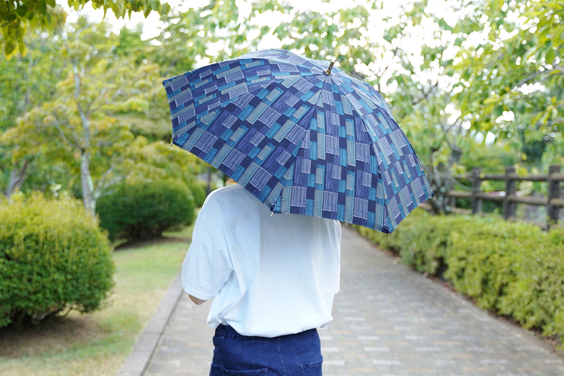 ダークブルー配色の晴雨兼用日傘を差す女性