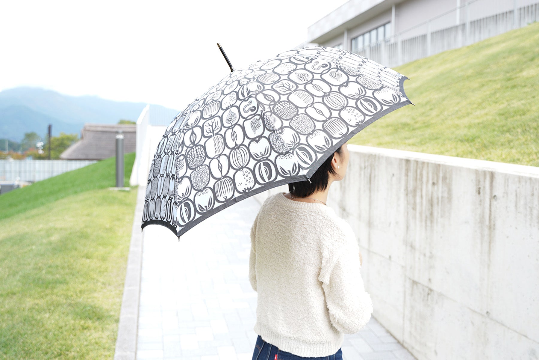 フルーツ柄の白と黒のレディース長傘を差す女性