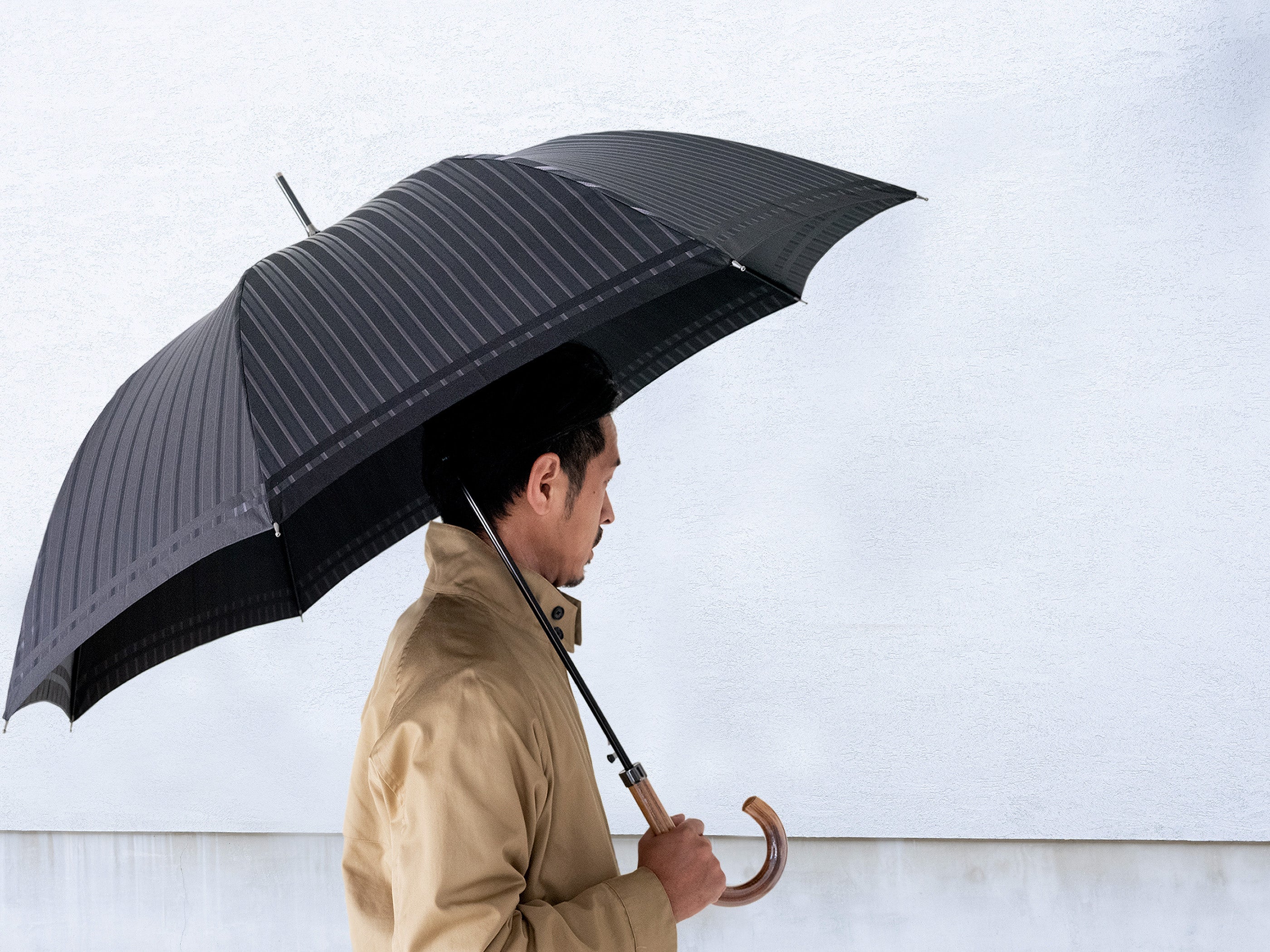 ストライプ柄のメンズ傘を差す男性