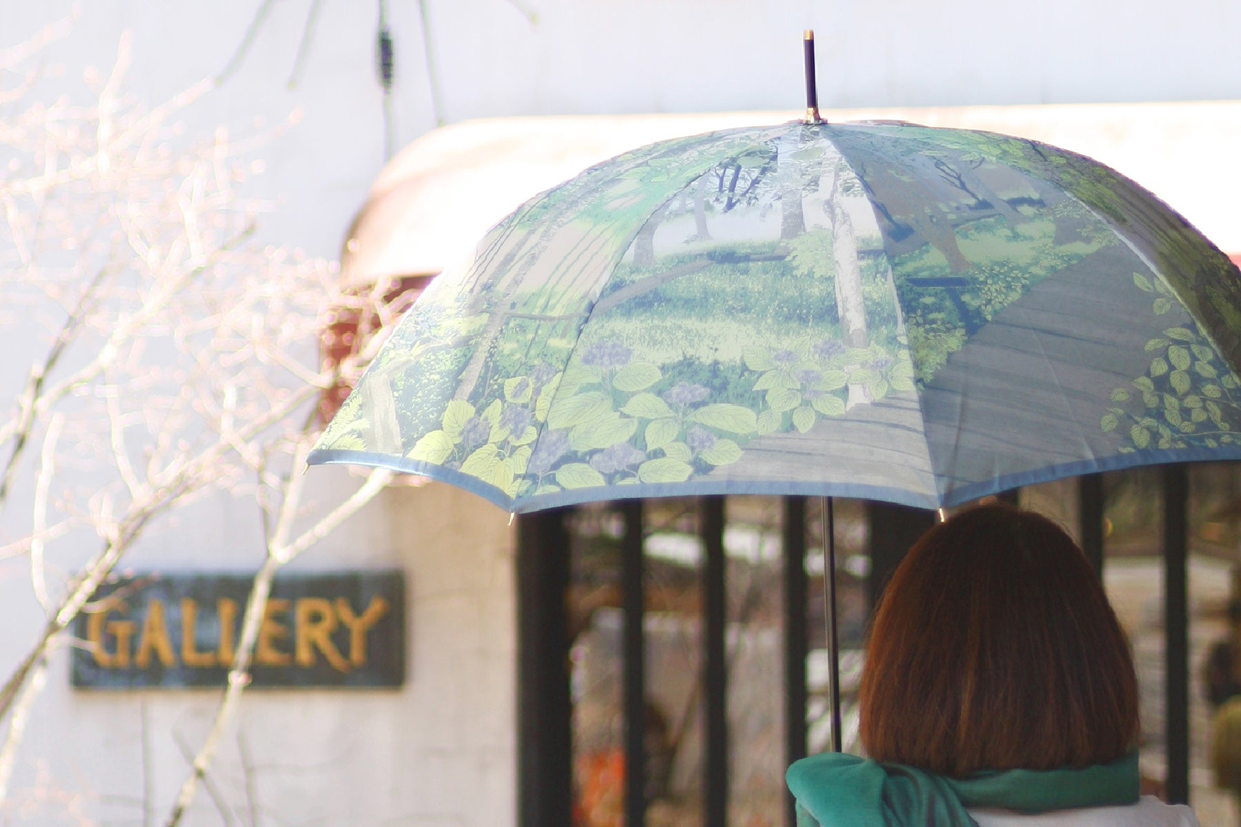 グリーン配色の草木を描いた晴雨兼用婦人傘を差す女性