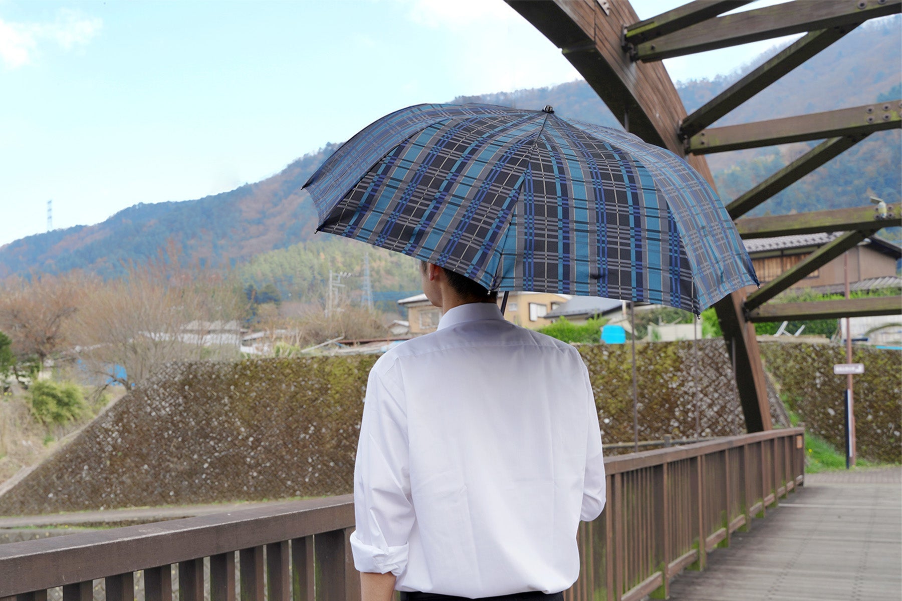 チェック柄のメンズ日傘を差す女性