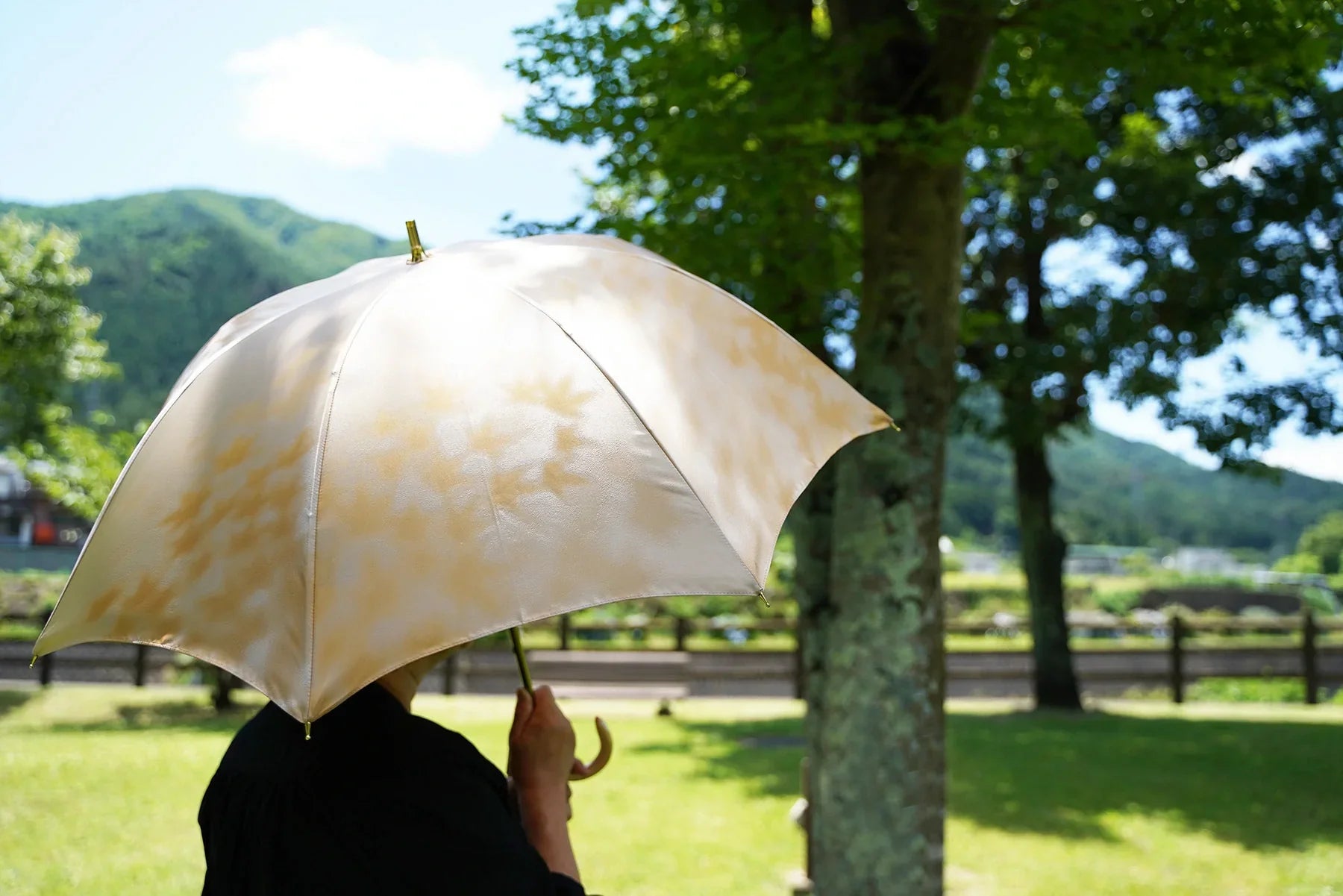 黄色の葉っぱ柄の日傘を差す女性