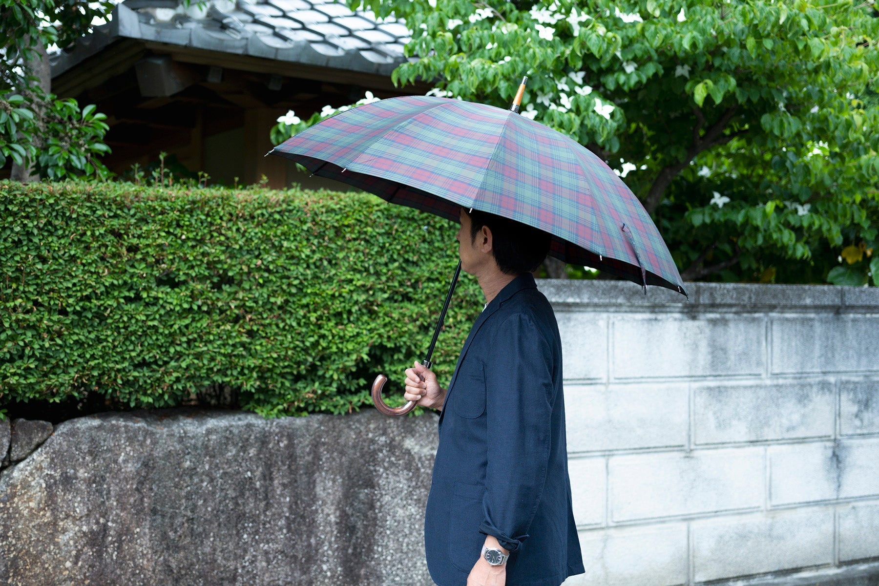チェック柄のメンズ長傘を差す男性