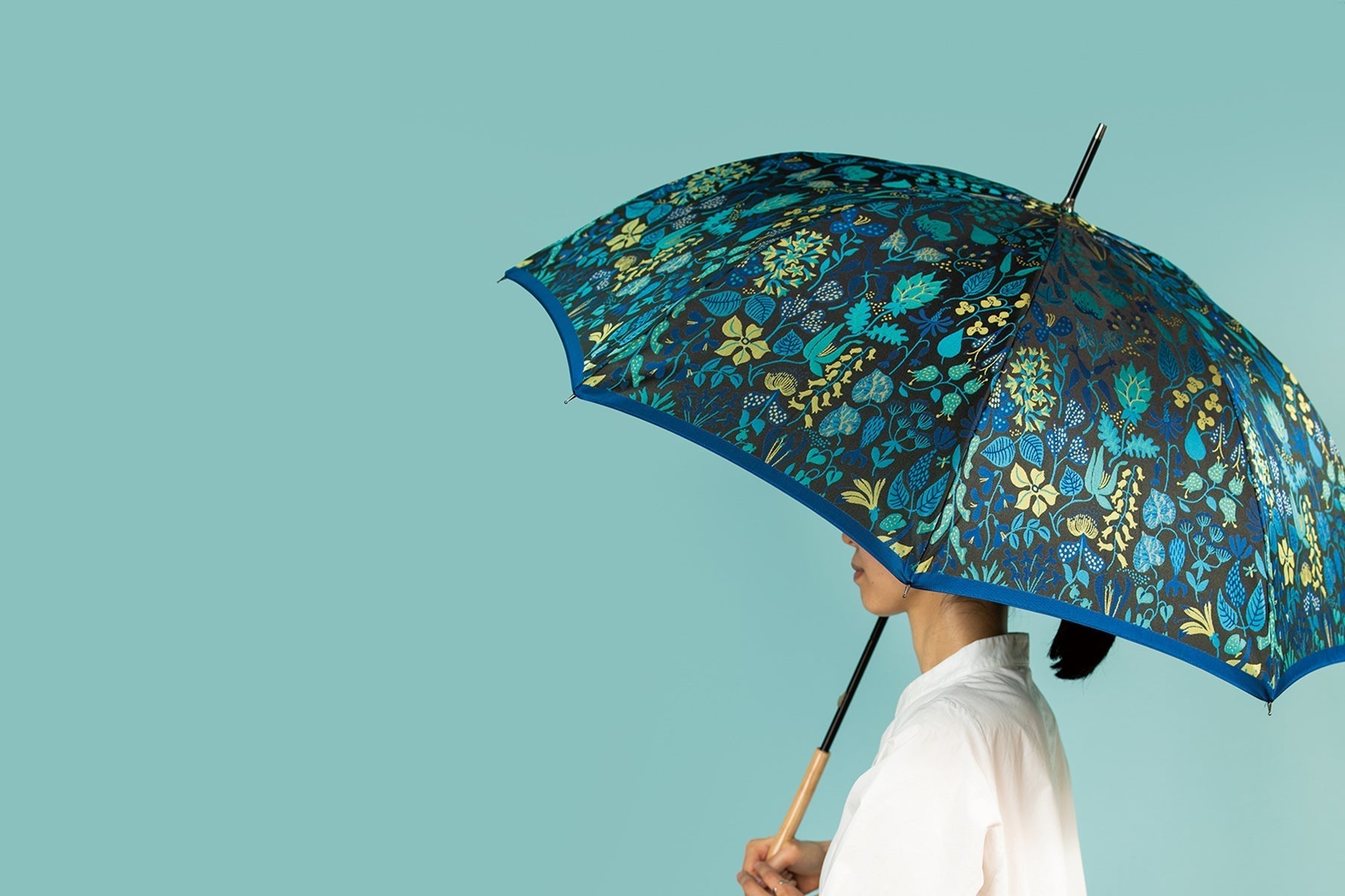 女性がブルーの植物柄のレディース傘を差している様子